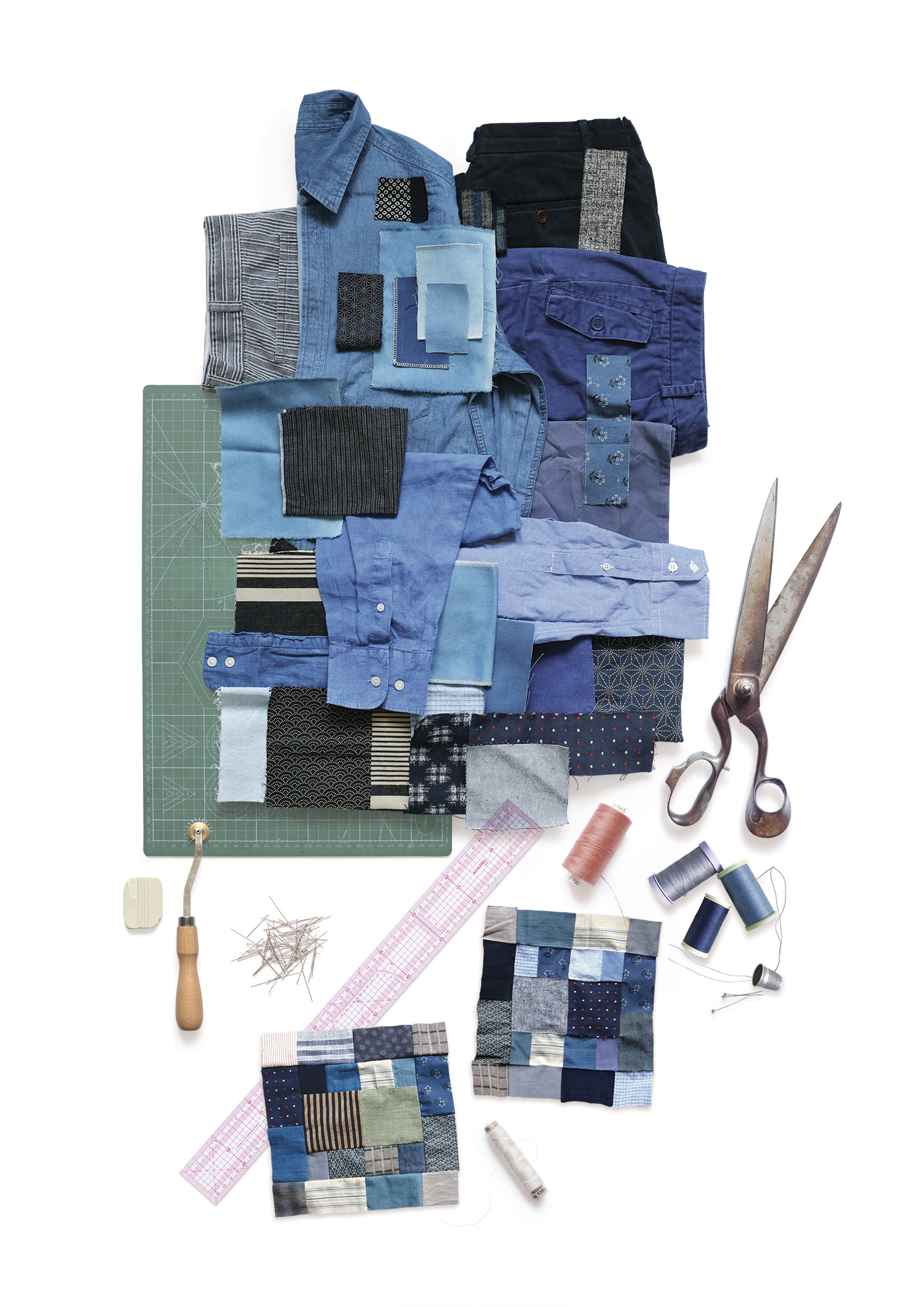 Garments and fabric pieces in blue tones with scissors, needles, ruler and thread spools for bespoke patchwork creation by Pénélope Westberg