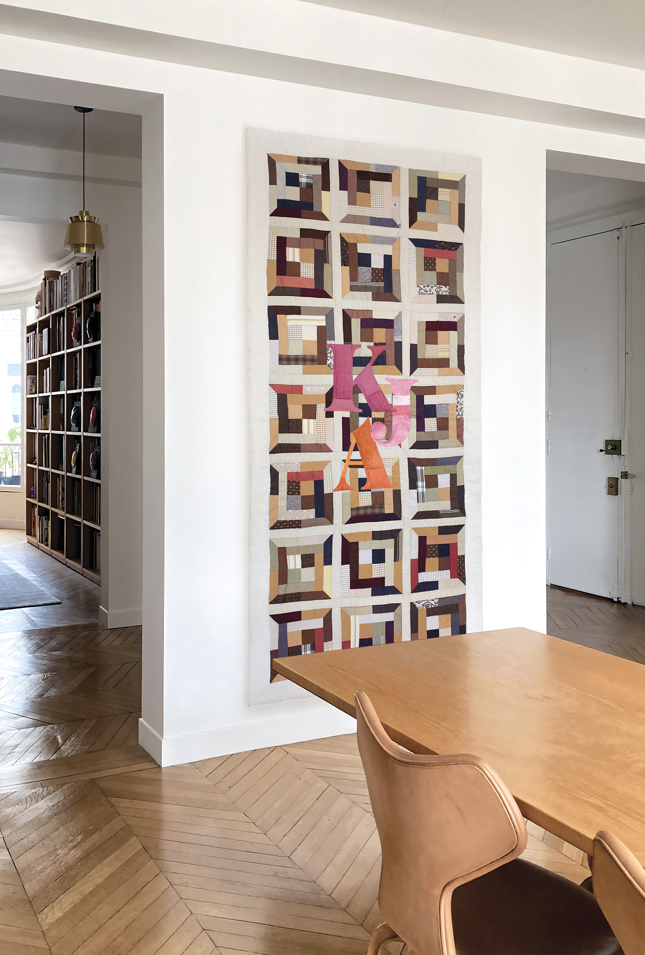 Hanging textile artwork in brown tones with pink and orange letters – memory patchwork by Pénélope Westberg