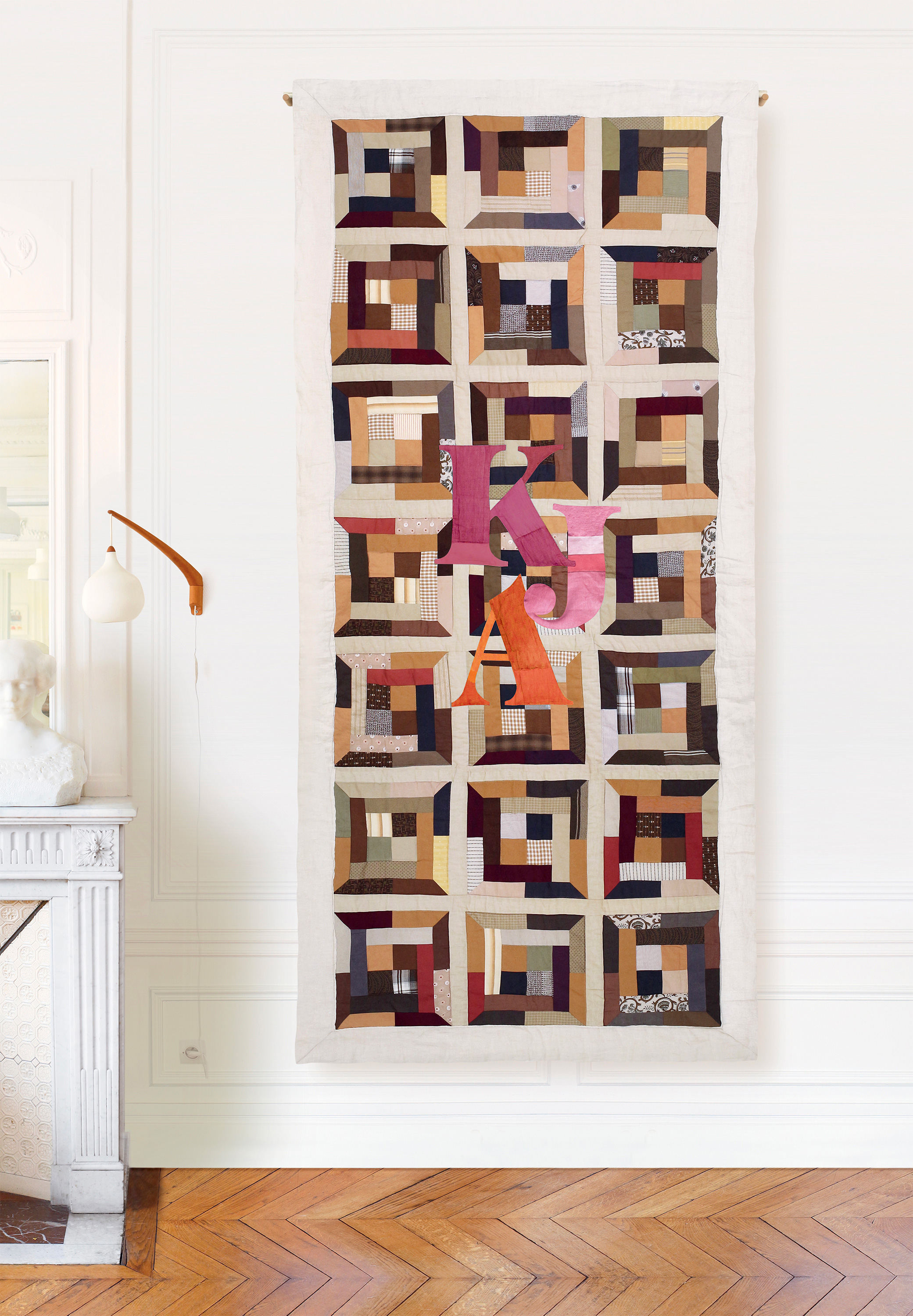 Brown, red, and orange patchwork wall hanging on beige background – contemporary textile set design by Pénélope Westberg