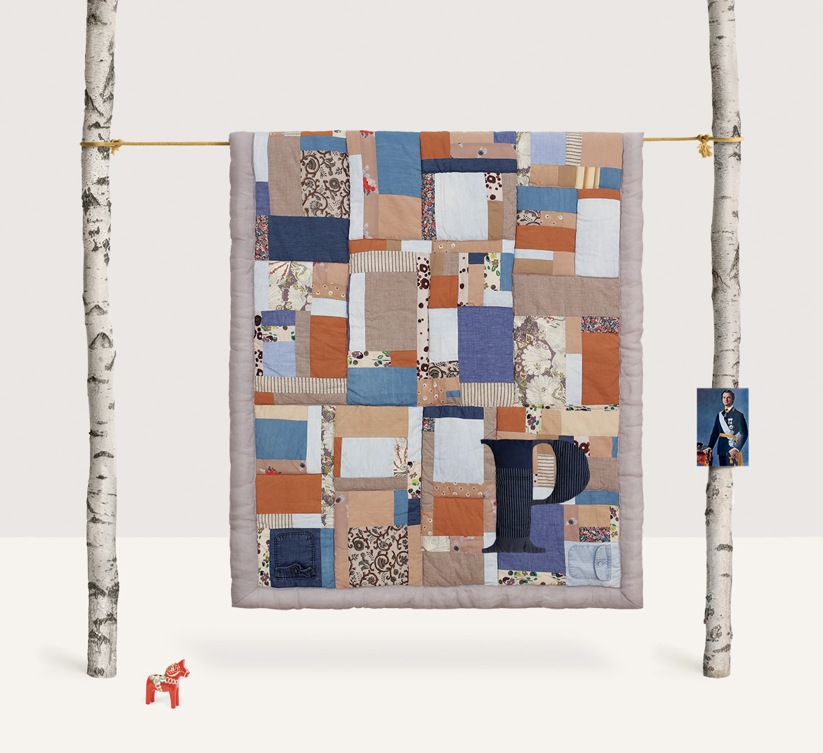 Blue, beige, and orange brown patchwork wall hanging on beige background – contemporary textile art by Pénélope Westberg
