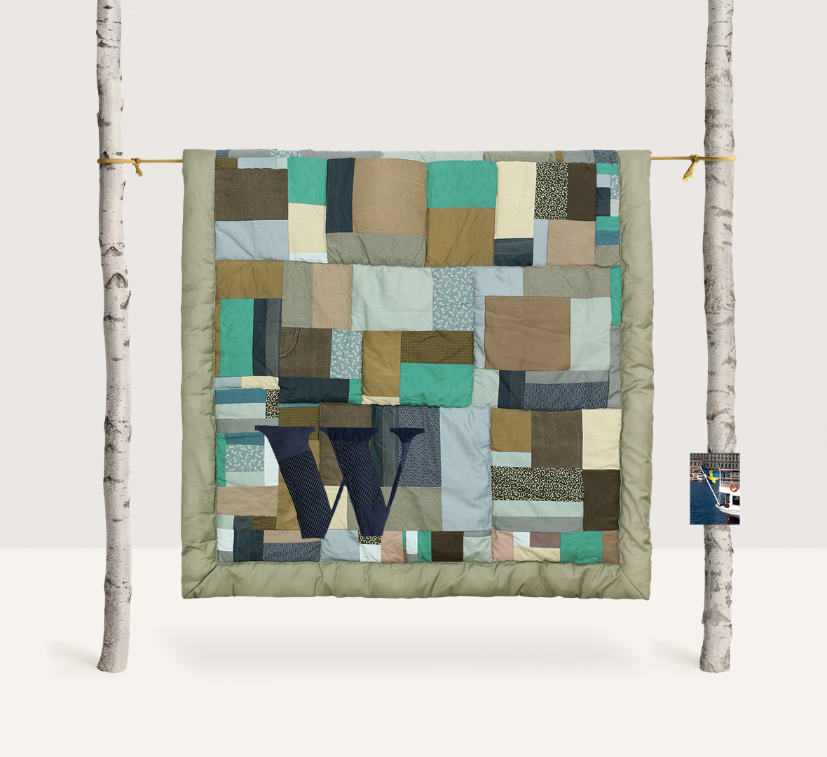 Green and light brown patchwork wall hanging on beige background – contemporary textile art an set design by Pénélope Westberg